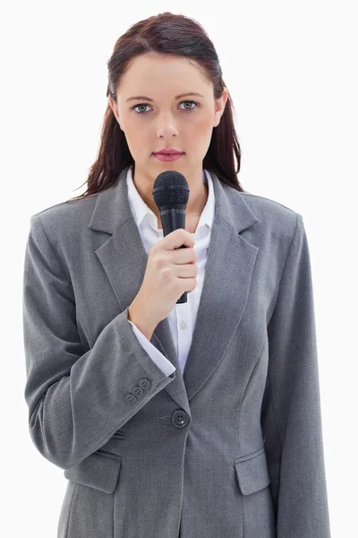 Primer plano de una mujer de negocios seria sosteniendo un micrófono — Foto de Stock