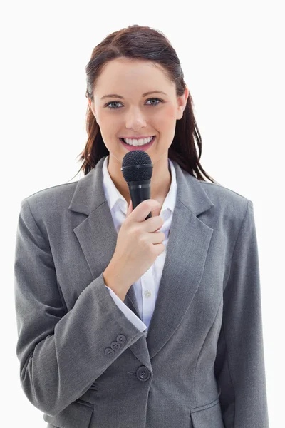 Mujer de negocios sonriendo y sosteniendo un micrófono — Foto de Stock