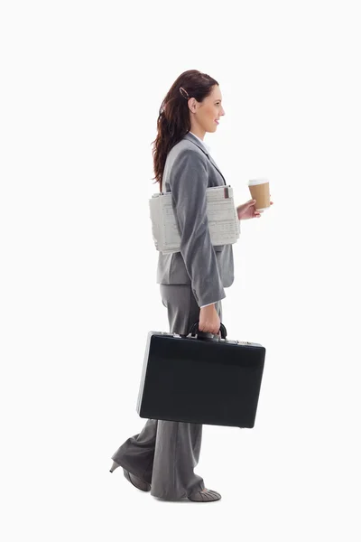 Perfil de una mujer de negocios que camina con un maletín, periódico a —  Fotos de Stock