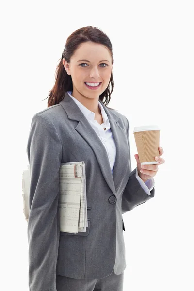 Businesswoman smiling with a newspaper and a coffee — Stock Photo, Image
