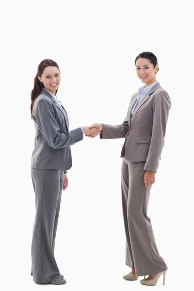 Two businesswomen shaking hands and smiling — Stock Photo, Image
