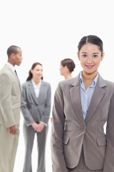 Empresaria sonriendo con compañeros de trabajo en el fondo —  Fotos de Stock