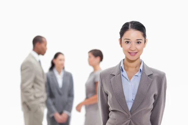 Businesswoman smiling with co-workers in the background — Stock Photo, Image