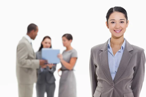 Empresaria sonriendo con compañeros de trabajo en el fondo —  Fotos de Stock