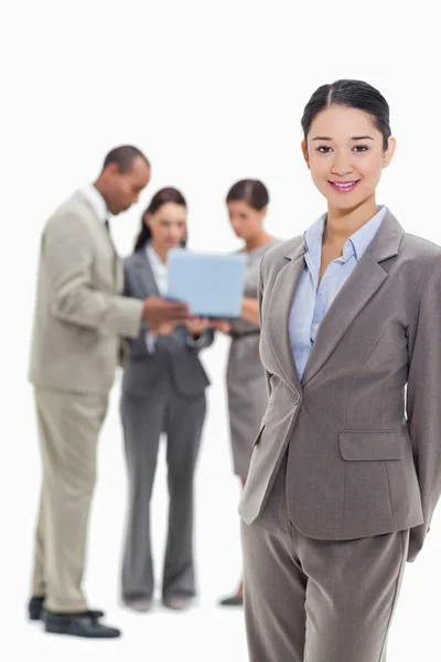 Businesswoman smiling with co-workers watching a laptop in the b — Stock Photo, Image