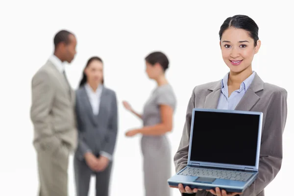 Businesswoman smiling showing a laptop screen with co-workers in — Stock Photo, Image