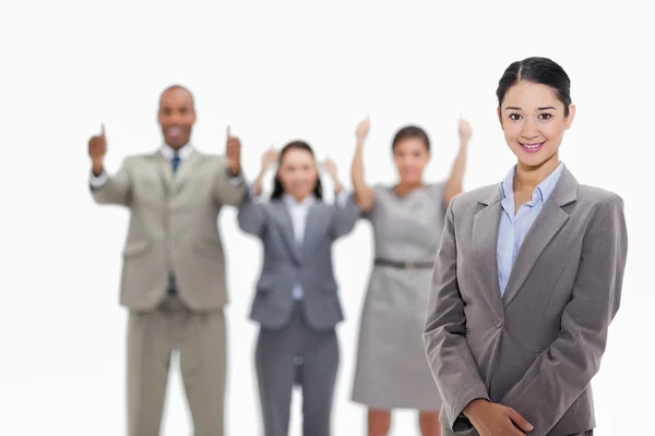 Businesswoman smiling with co-workers approving in the backgroun — Stock Photo, Image