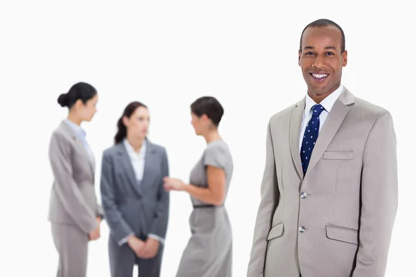 Businessman with co-workers talking in the background — Stock Photo, Image