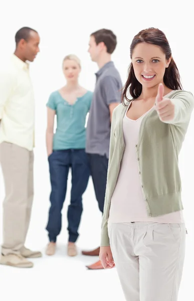 Girl smiling and giving the thumbs-up with friends — Stock Photo, Image