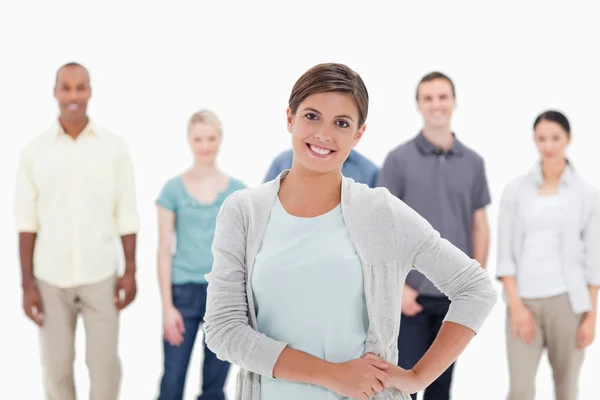 Close-up of a woman smiling with her hands on her hip with peopl — Stock Photo, Image