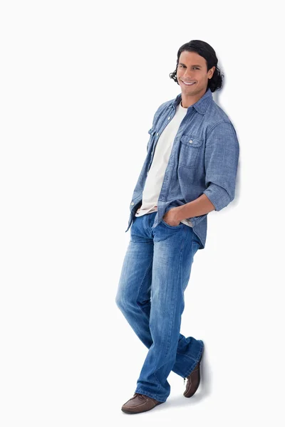 Man smiling while leaning against a wall — Stock Photo, Image