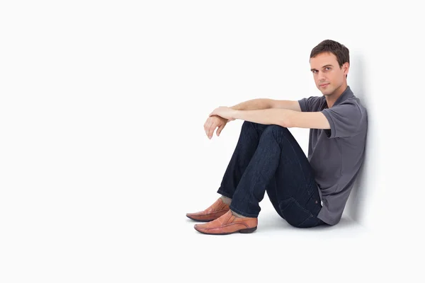 Mann sitzt gegen eine Wand — Stockfoto