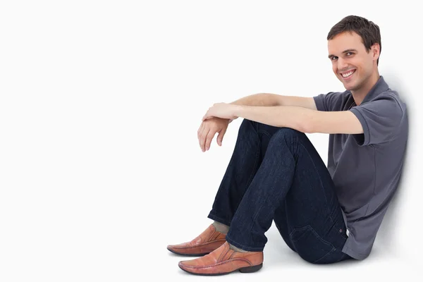 Närbild av en man som ler när han satt mot en vägg — Stockfoto