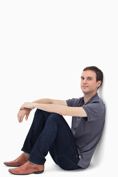 Zbliżenie: ciemnobrązowe włosy mężczyzna siedzi na ścianie — Zdjęcie stockowe