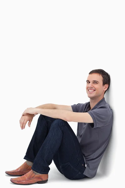 Gros plan d'un homme brun foncé assis contre un mur — Photo