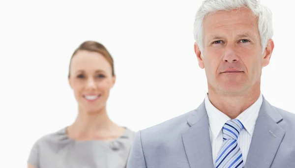 Close-up of a serious white hair businessman with a woman smilin — Stock Photo, Image