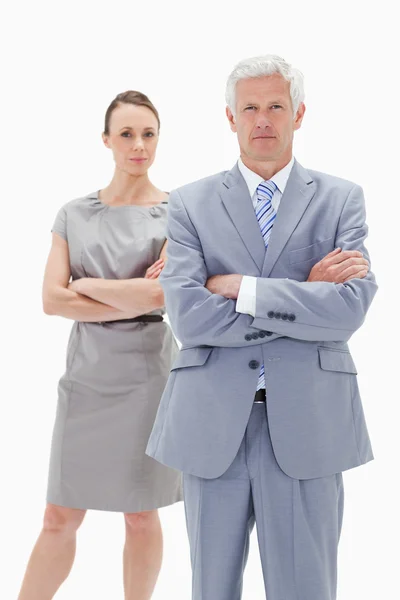 Serious white hair businessman with a woman behind him crossing — Stock Photo, Image