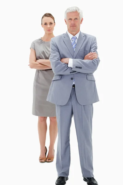 Homem de negócios de cabelo branco com uma mulher no fundo cruzando sua — Fotografia de Stock