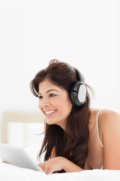 Woman looking forward and smiling while using a tablet and headp — Stock Photo, Image