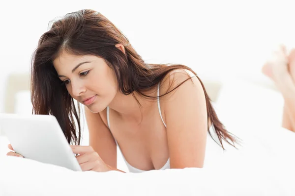 同时使用一台 tablet pc 与交叉的双腿在床上躺的女人 — 图库照片