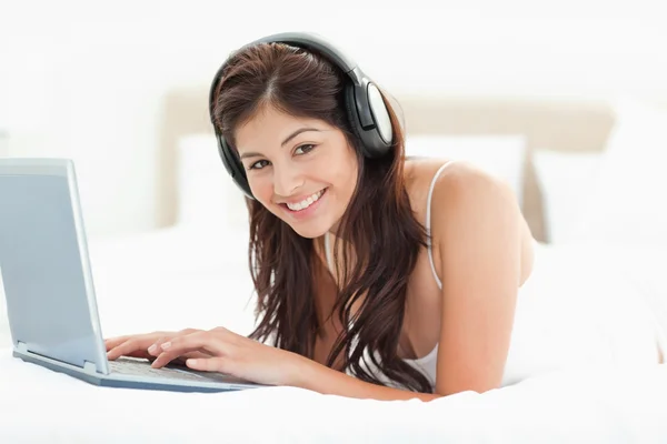 Woman looking forward and smiling while browsing though a laptop — Stock Photo, Image
