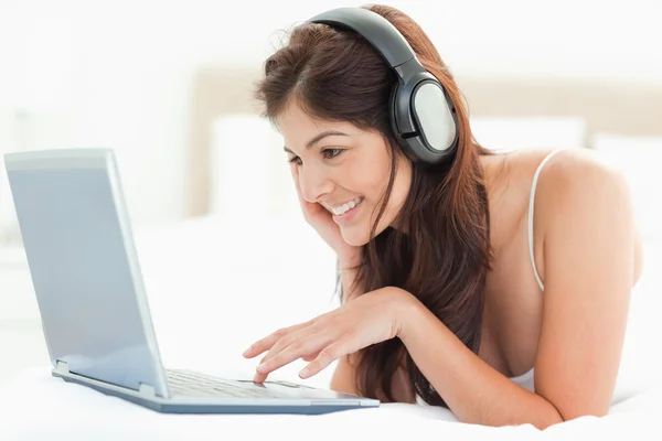 Mujer sonriente usando la almohadilla del ratón para desplazarse en un ordenador portátil mientras nosotros —  Fotos de Stock