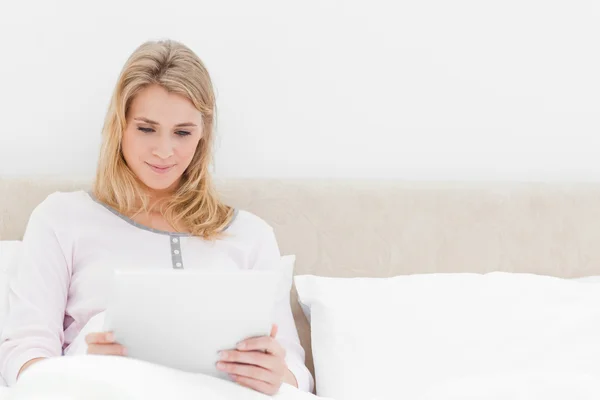 Žena sedí v posteli, držení a sledovat počítače tablet pc — Stock fotografie