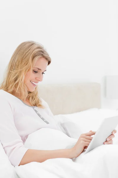Vue latérale, Femme au lit avec tablette PC, regarder et sourire — Photo