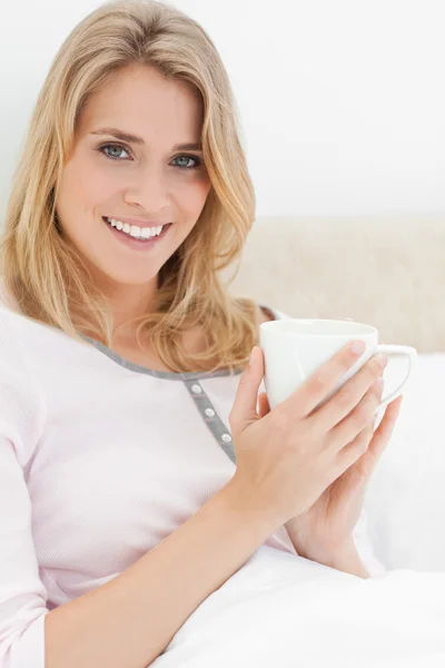 Närbild, kvinna i sängen, med cup i händer som hon ser fram emot s — Stockfoto