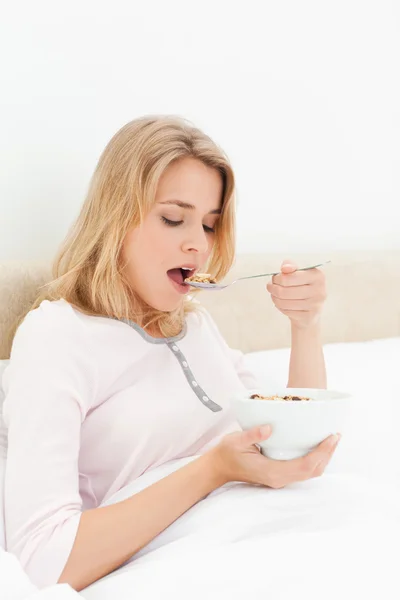 Mujer en la cama, con la boca abierta a punto de comer una cucharada de cereal —  Fotos de Stock