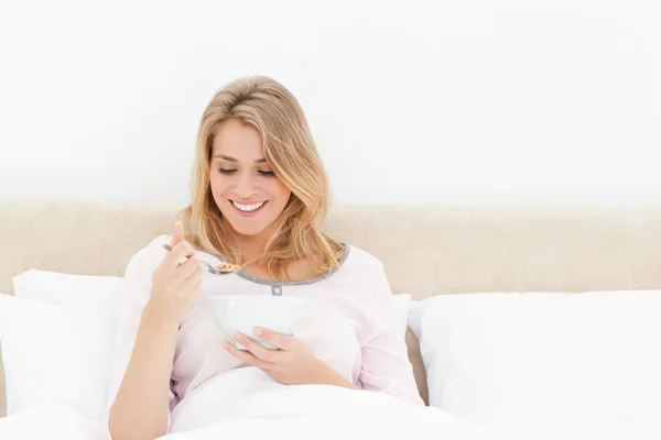 Mujer mirando una cuchara de cereal mientras está sentada en la cama — Foto de Stock