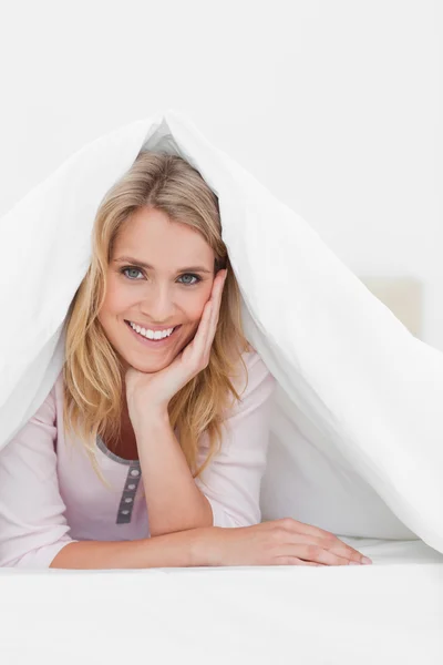 Närbild, kvinnan under täcke med handen på huvudet, leende — Stockfoto