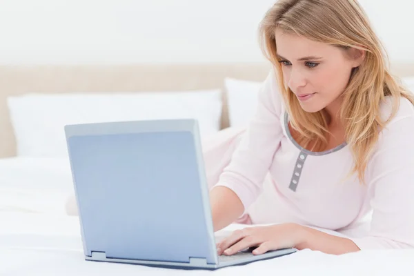Woman lying on the bed, while using a laptop — Stock Photo, Image