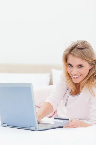 Woman lying on the bed, laptop beside her as she looks forward s — Stock Photo, Image
