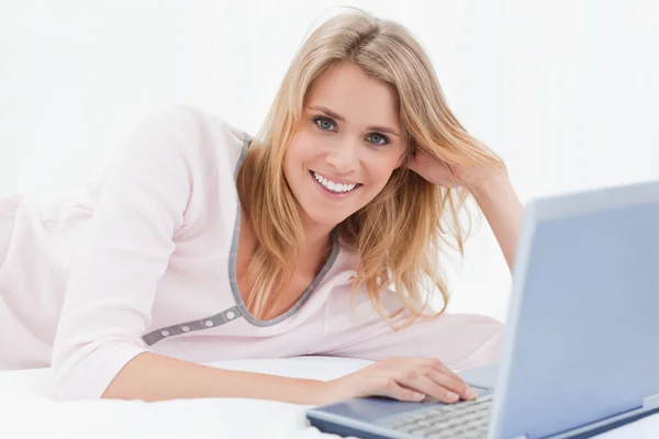 Mujer acostada en la cama, con su portátil, mientras mira hacia adelante un —  Fotos de Stock