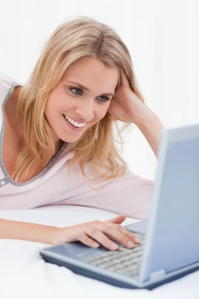 Nahaufnahme, Frau benutzt ihren Laptop, schaut auf den Bildschirm und lächelt — Stockfoto