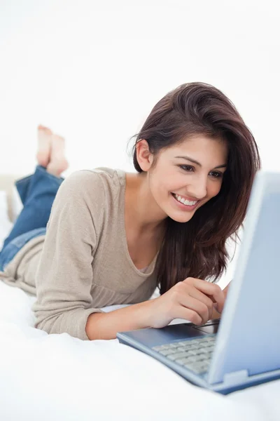 Close up, donna sdraiata sul letto sorridente con il suo computer portatile in fron — Foto Stock