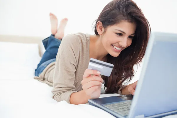 Mujer en su portátil con tarjeta de crédito en la mano y sonriendo —  Fotos de Stock
