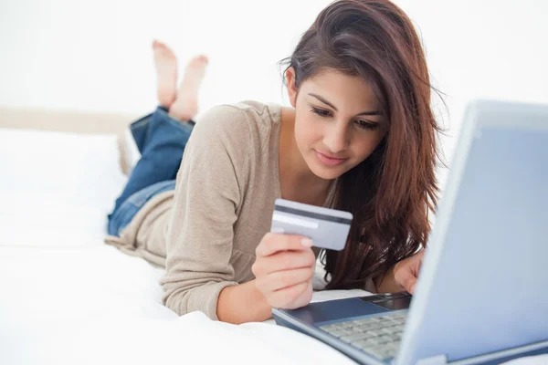 Γυναίκα κοιτάζοντας τα στοιχεία της πιστωτικής κάρτας, καθώς χρησιμοποιεί το laptop — Φωτογραφία Αρχείου