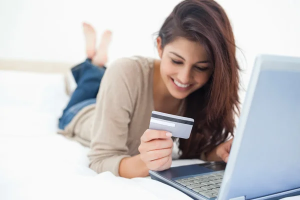 Gülümseyen kadın onun laptop t olarak onun kredi kartı bilgilerini okuma — Stok fotoğraf