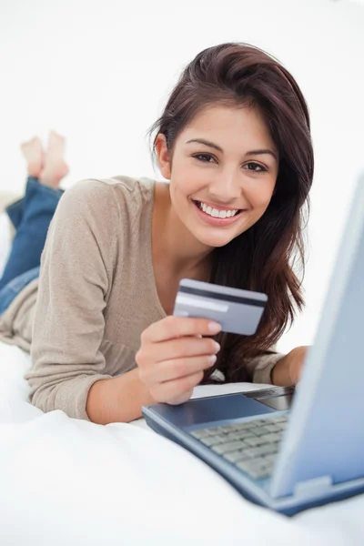 Nahaufnahme, Frau mit Kreditkarte und Laptop auf dem Bett lächelnd — Stockfoto