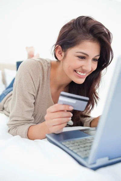 De cerca, mujer con tarjeta de crédito mirando a la computadora portátil y sonriendo —  Fotos de Stock
