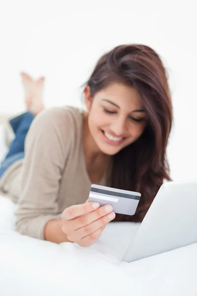 Close up, concentrando-se no cartão de crédito, realizada por uma mulher sorridente sobre ele — Fotografia de Stock