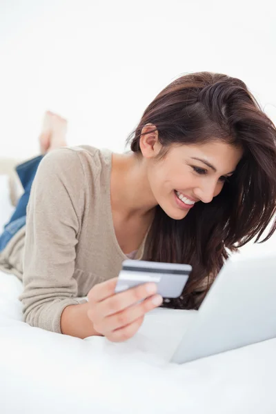 Frau lächelt, während sie ihr Tablet und ihre Kreditkarte benutzt — Stockfoto