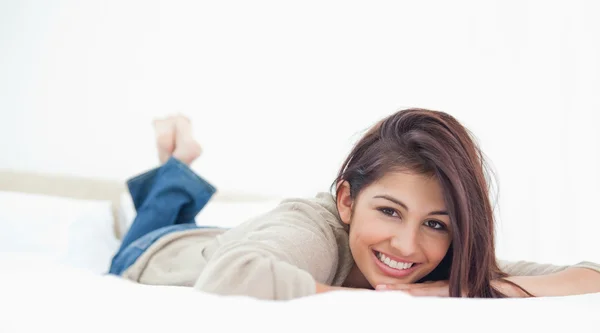 Bajo ángulo, mujer acostada en la cama, sonriendo con las piernas cruzadas — Foto de Stock