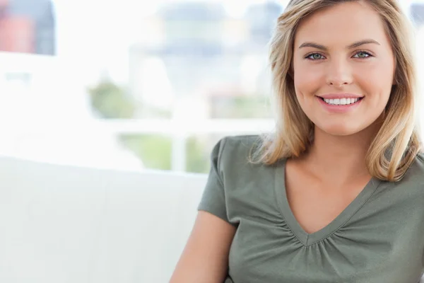 Close up, mulher sorrindo enquanto ela se senta em um sofá — Fotografia de Stock