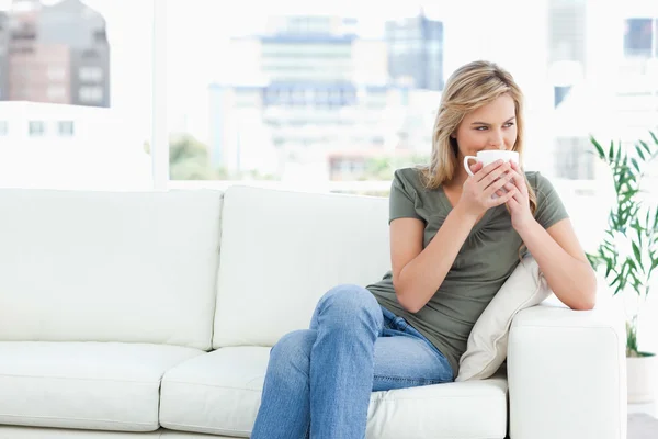 Woman holding a mug up to her nose as she looks to the side whil — Stock Photo, Image