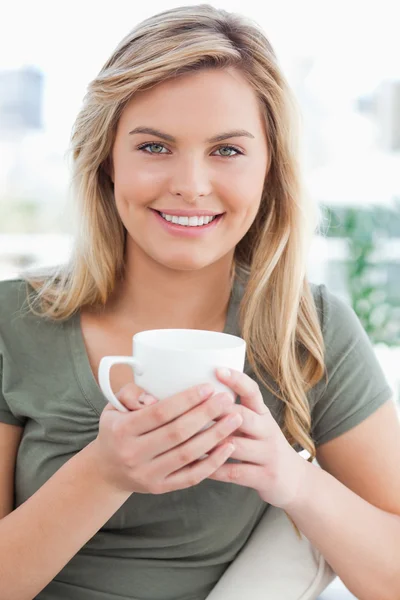 Close up, woman smiling, with mug in her hands and looking ahead — Stock Photo, Image