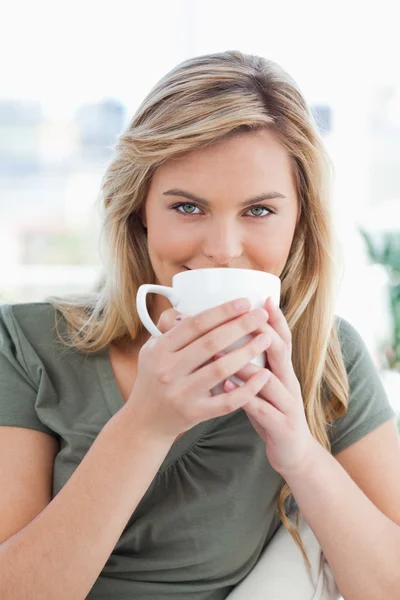 Close up, woman with a mug held up in front of her mouth and loo — Stock Photo, Image