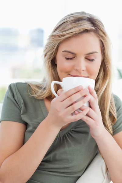 Woman, with eyes closed smelling the drink in her cup, held in u — Stock Photo, Image